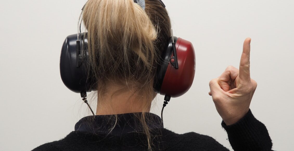 a woman wearing headphones pointing to the side